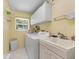 Bright laundry room with washer, utility sink, storage cabinets, and a window for natural light at 4461 La France Ave, North Port, FL 34286