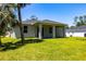 Image of the back of house and spacious backyard with well maintained green grass and tropical trees at 4880 Cornsilk Ter, North Port, FL 34286
