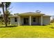 Image of the back of house and spacious backyard with well maintained green grass and tropical trees at 4880 Cornsilk Ter, North Port, FL 34286