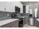 Modern kitchen with stainless steel appliances, sleek cabinets, and stylish backsplash at 4880 Cornsilk Ter, North Port, FL 34286