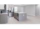 Bright kitchen featuring an island, stainless steel appliances, gray cabinets, and light wood floors at 4880 Cornsilk Ter, North Port, FL 34286