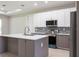 Modern kitchen featuring stainless appliances, white upper cabinets, a central island, and light wood flooring at 4880 Cornsilk Ter, North Port, FL 34286