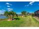 Landscaped backyard overlooking a serene lake featuring palm trees, green lawn, and decorative ornaments at 7501 Mikasa Dr, Punta Gorda, FL 33950