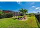 Beautiful backyard featuring a screened lanai, decorative landscaping, black metal fence, and lush green grass at 7501 Mikasa Dr, Punta Gorda, FL 33950