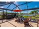 View of the patio area showcasing outdoor seating, grill, and serene lake views within the screened enclosure at 7501 Mikasa Dr, Punta Gorda, FL 33950