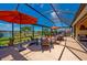 Screened patio with comfortable seating, outdoor umbrellas, and scenic pond views for relaxing or entertaining at 7501 Mikasa Dr, Punta Gorda, FL 33950