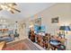 Well-lit living room with a ceiling fan, a large TV, decor shelving, and a view of the hallway and kitchen at 9850 Fiddlers Green Cir # 130, Rotonda West, FL 33947