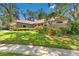 Landscaped front yard featuring lush green grass, colorful plants and shrubs and mature trees creating shade at 1102 Hunt Club Ln, Valrico, FL 33594