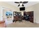 Well-lit home office featuring built-in shelving, desk, ceiling fan, and a glimpse into an adjacent sitting area at 1134 Coronado Dr, Punta Gorda, FL 33950