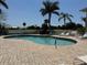 Sparkling community pool surrounded by a paved patio with lounge chairs and mature palm trees at 1295 Saxony Cir # 2101, Punta Gorda, FL 33983