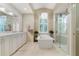 An elegant bathroom features a soaking tub next to a window and a glass shower at 13761 Long Lake Ln, Port Charlotte, FL 33953
