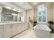 A well-lit bathroom features a modern tub, a large mirror over double sinks, and a beautiful chandelier at 13761 Long Lake Ln, Port Charlotte, FL 33953