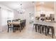 Dining area and kitchen with a bar, featuring a long wooden table and modern light fixture at 1690 Yakutat Rd, North Port, FL 34287