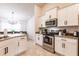 Well-lit kitchen with stainless steel appliances and white cabinetry, with a view into the dining area at 1690 Yakutat Rd, North Port, FL 34287