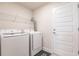 Clean laundry room with modern, white front-loading machines and wire shelving at 1690 Yakutat Rd, North Port, FL 34287