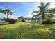 Sprawling backyard with mature palm trees offers a picturesque view of the waterfront and lush landscaping at 1796 Boca Raton Ct, Punta Gorda, FL 33950