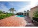 Backyard pool area with brick patio, tall palm tree, and green landscaping at 1796 Boca Raton Ct, Punta Gorda, FL 33950