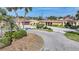 Front of a charming home with a circular driveway, lush landscaping, well-maintained lawn, and a two-car garage at 1796 Boca Raton Ct, Punta Gorda, FL 33950