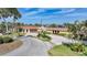 Home featuring a circular driveway, beautiful landscaping, green lawn, two-car garage, and lush trees at 1796 Boca Raton Ct, Punta Gorda, FL 33950