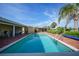 Sparkling in-ground pool surrounded by brick patio, covered porch, and lush landscaping at 1796 Boca Raton Ct, Punta Gorda, FL 33950