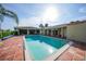 Clean and refreshing in-ground pool with brick patio, covered porch, and tropical greenery at 1796 Boca Raton Ct, Punta Gorda, FL 33950