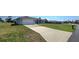 Wide concrete driveway leading to a light gray home with green grass lawn and light-colored brickwork at 18519 Alphonse Cir, Port Charlotte, FL 33948