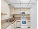 Efficient kitchen featuring white appliances, ample cabinet space, and a double stainless steel sink under fluorescent lighting at 19505 Quesada Ave # Pp201, Port Charlotte, FL 33948