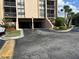 Exterior view of the building's garage entrance with palm trees, landscaping, and visible parking spaces at 21405 Olean Blvd # 531, Port Charlotte, FL 33952