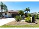 Charming single-story home featuring a well-manicured lawn, an attached two-car garage, and lush tropical landscaping at 25179 Campos Dr, Punta Gorda, FL 33983