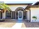 Inviting front entrance with arched doorway, decorative security door, and manicured landscaping at 25179 Campos Dr, Punta Gorda, FL 33983