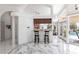 Open-concept kitchen features white marble-patterned floors, breakfast bar, and access to the screened lanai with pool views at 25179 Campos Dr, Punta Gorda, FL 33983