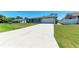 Single-story home with an expansive driveway leading to a one-car garage, surrounded by a lush green lawn at 309 Aurora St, Port Charlotte, FL 33948
