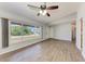Sunlit living room featuring wood-look floors, a ceiling fan, and a large window overlooking the front yard at 309 Aurora St, Port Charlotte, FL 33948