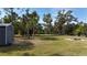 The spacious backyard features a storage shed, lush greenery, and ample room for outdoor activities and storage at 3136 Joshua St, Port Charlotte, FL 33948