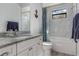 Bright bathroom with a white vanity, granite countertop, and tub with tiled walls at 3136 Joshua St, Port Charlotte, FL 33948