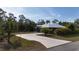 Modern home boasts a metal roof and long driveway, framed by lush greenery and an American flag at 3136 Joshua St, Port Charlotte, FL 33948