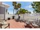 Outdoor patio featuring a red-brick surface, ample seating, and a lush green lawn beyond a white picket fence at 3305 Blue Jay Ln, Englewood, FL 34224