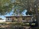 Exterior shot of the back of the home with white siding, windows, and a tire swing in the yard at 3538 Pinetree St, Port Charlotte, FL 33952