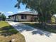 Exterior shot of a home with a long driveway, white siding, an attached garage, and multiple windows at 3538 Pinetree St, Port Charlotte, FL 33952