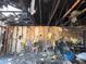 Living room damaged by fire with missing walls, burnt ceiling, and destroyed furniture at 3538 Pinetree St, Port Charlotte, FL 33952