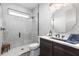 Modern bathroom with a walk-in shower, gray tile, vanity, and a unique octagonal mirror at 3729 Peace River Dr, Punta Gorda, FL 33983