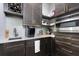 Modern wet bar featuring a sink, wine rack, microwave, stylish backsplash, and dark wood cabinetry with sleek gold hardware at 3729 Peace River Dr, Punta Gorda, FL 33983