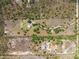 Aerial view shows the land in a rural area with trees. It contains the home and outbuildings surrounded by trails at 47350 Bermont Rd, Punta Gorda, FL 33982