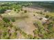 Aerial view showcases vast acreage, including a single-story residence, a large field, and lush trees in the vicinity at 47350 Bermont Rd, Punta Gorda, FL 33982