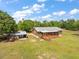 Charming single-story house with a metal roof, a screened porch, and a detached garage/workshop on a sprawling green lawn at 47350 Bermont Rd, Punta Gorda, FL 33982