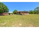 Exterior of house, features a single story, screen porch, detached garage with lean-to on a sprawling green lawn at 47350 Bermont Rd, Punta Gorda, FL 33982