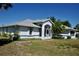 Exterior view of home with an arched entryway, lush tropical landscaping, and fresh paint at 5050 Prosch Cir, North Port, FL 34288