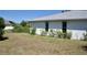 Side exterior view of the home with overgrown flowerbeds at 5050 Prosch Cir, North Port, FL 34288
