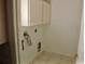 Functional laundry room with tiled floor, overhead cabinets, and washer/dryer hookups at 5050 Prosch Cir, North Port, FL 34288