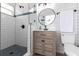 Bathroom features walk-in shower, round mirror, wood vanity, and white subway tile at 8115 Manasota Key Rd, Englewood, FL 34223